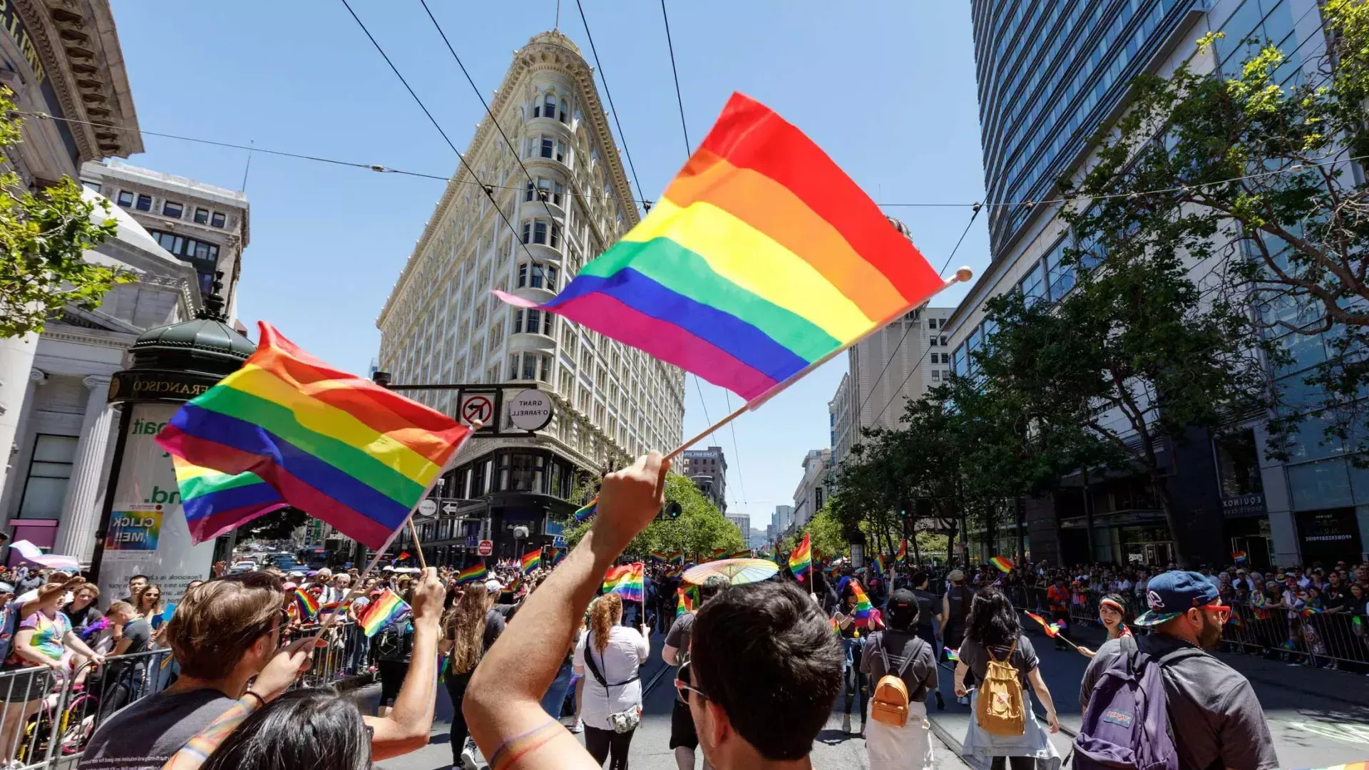 Passanten der San Francisco Pride Parade schwenken Regenbogenfahnen.
